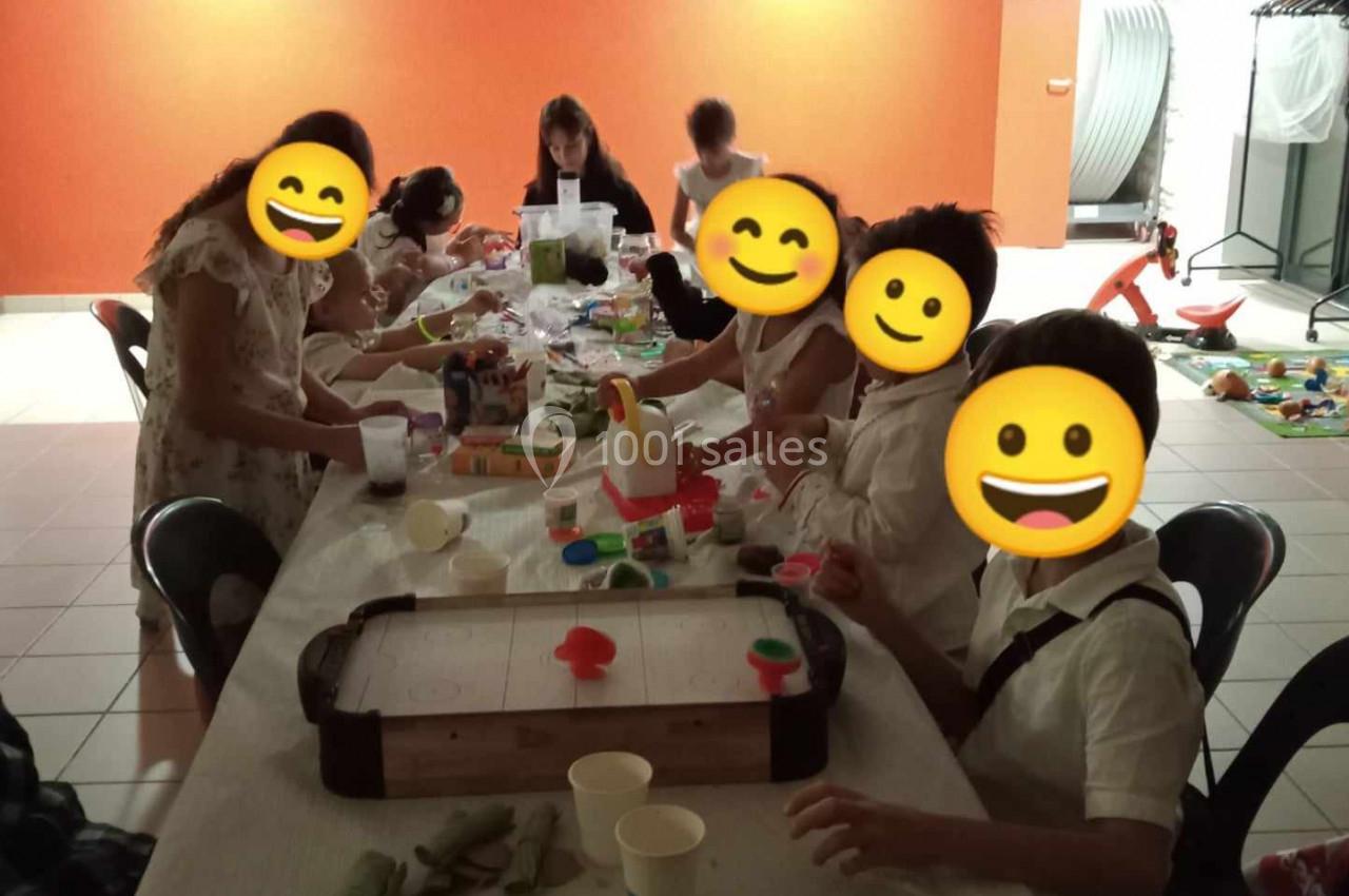 Des personnes assises autour d'une table participent à une activité manuelle dans une salle éclairée.