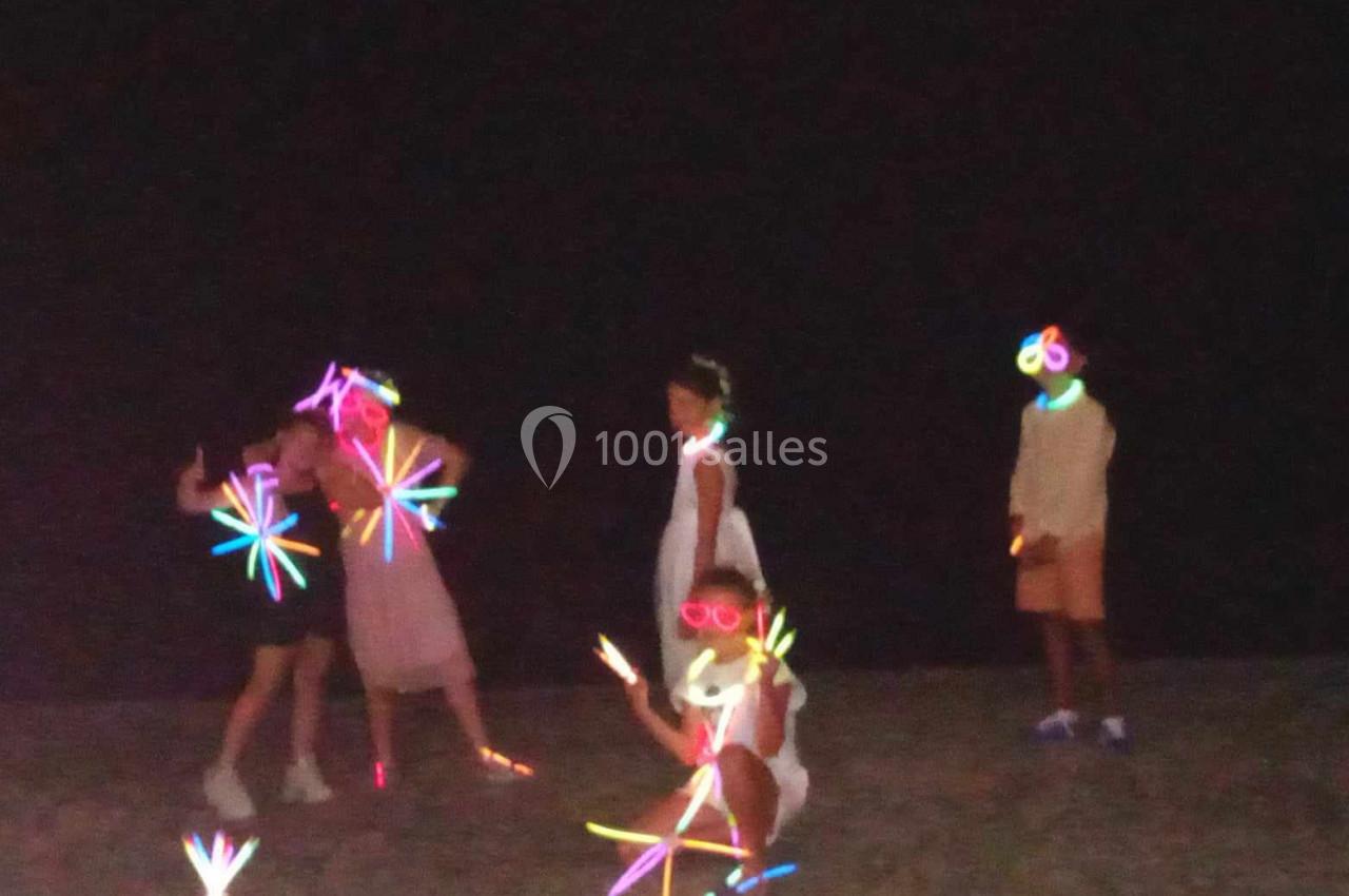 Des enfants jouent dans l'obscurité avec des bâtons lumineux colorés.