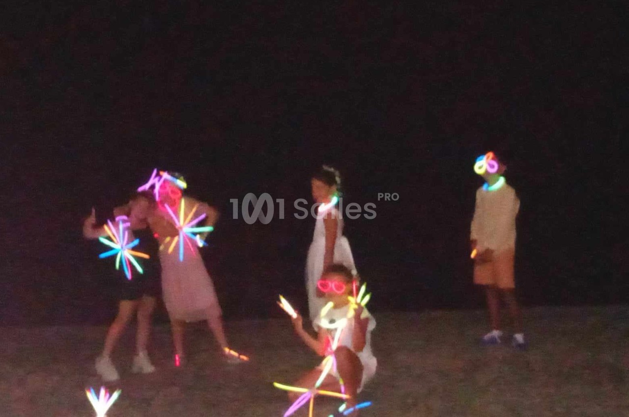 Des enfants jouent dans l'obscurité avec des bâtons lumineux colorés.