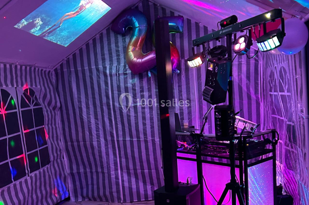 Installation de matériel de son et lumière dans une tente décorée pour une fête, avec des projections au plafond.