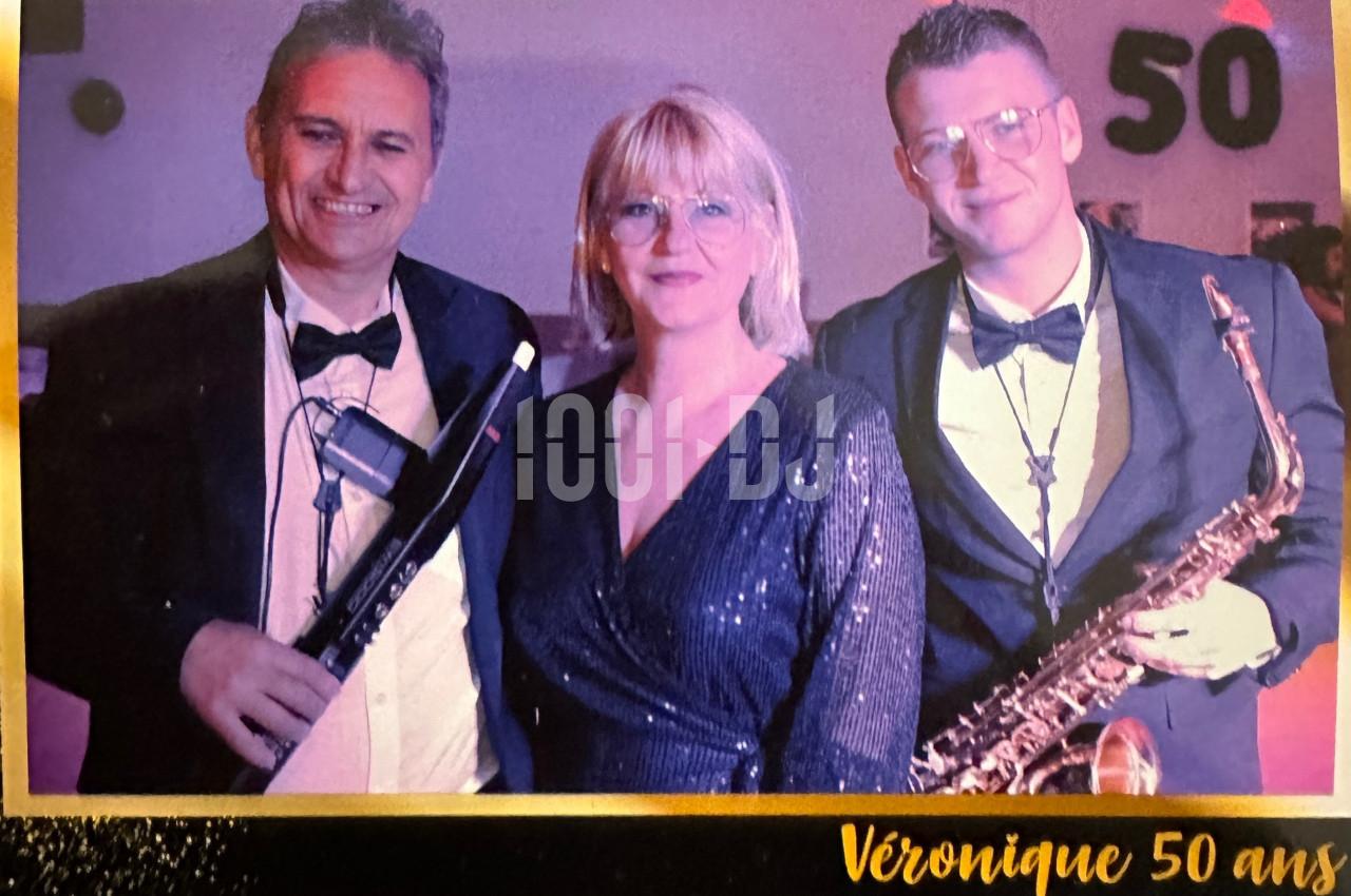 Trois personnes posent en tenue de soirée, deux hommes tenant des instruments de musique et une femme au centre.