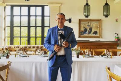 Miniature DJ Carcès (Var) - Dj Sax à Tout Coeur #24 Un homme en costume bleu tient un saxophone dans un intérieur lumineux avec de grandes fenêtres.