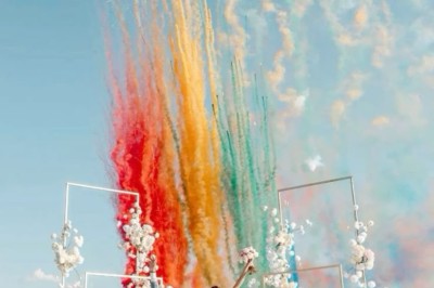 Un homme en costume bleu tient un saxophone sous une pergola décorée de fleurs blanches.