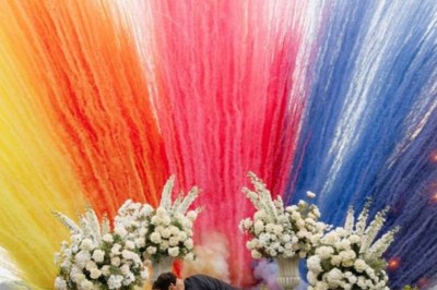 Un homme en costume bleu tient un saxophone sous une pergola décorée de fleurs blanches.