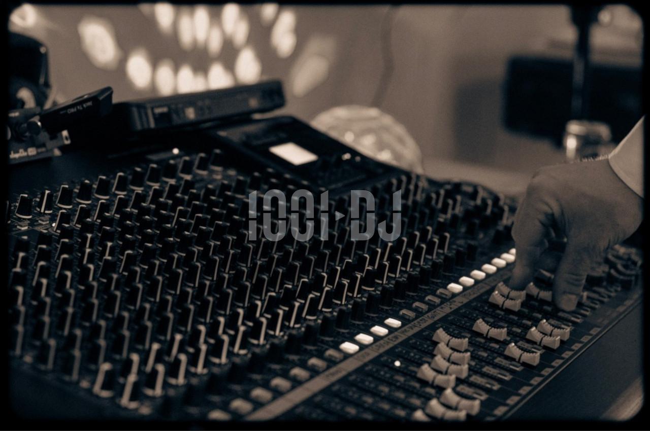 Main ajustant les curseurs d'une console de mixage audio dans un environnement faiblement éclairé.