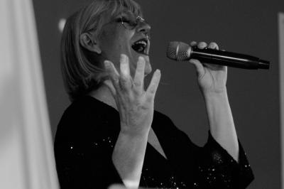 Un homme en costume bleu tient un saxophone dans un intérieur lumineux avec de grandes fenêtres.