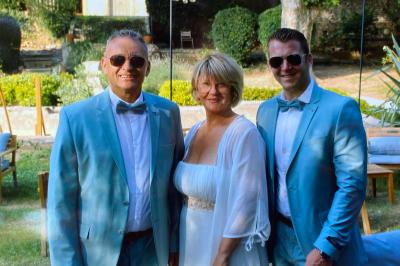 Un homme en costume bleu tient un saxophone dans un intérieur lumineux avec de grandes fenêtres.