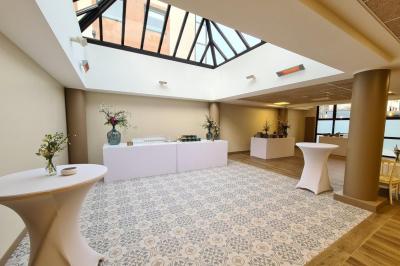 Salle décorée avec des ballons roses, éclairage violet, deux personnes marchant au centre, tables hautes et chaises…