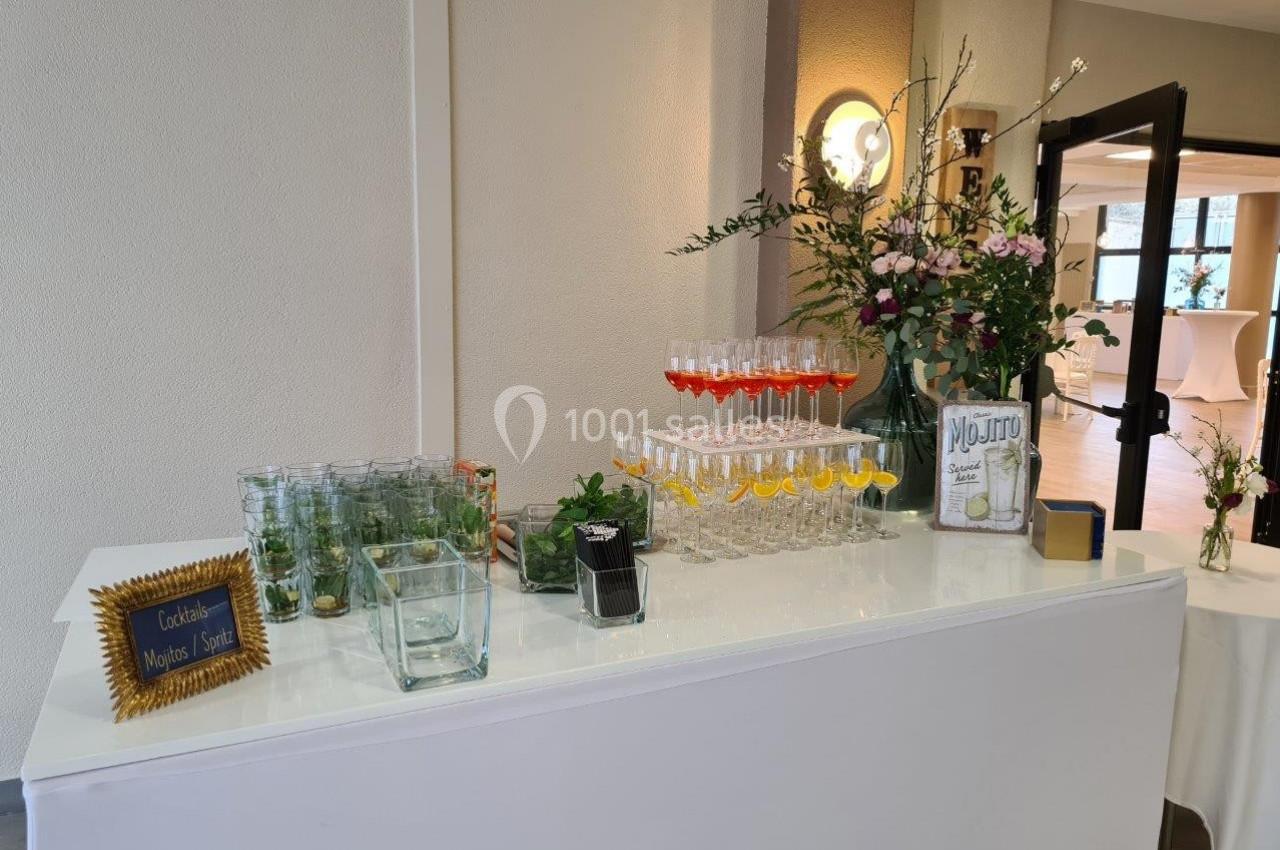 Bar à cocktails avec verres alignés, décoré de fleurs, d'agrumes et d'une pancarte indiquant ’Mojito’.