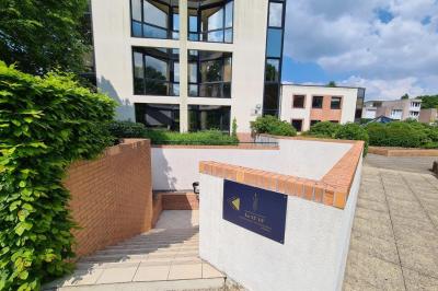 Salle décorée avec des ballons roses, éclairage violet, deux personnes marchant au centre, tables hautes et chaises…