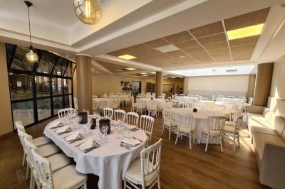 Salle décorée avec des ballons roses, éclairage violet, deux personnes marchant au centre, tables hautes et chaises…