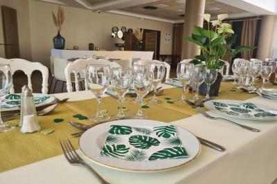 Salle décorée avec des ballons roses, éclairage violet, deux personnes marchant au centre, tables hautes et chaises…