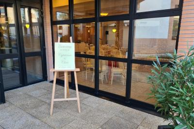 Salle décorée avec des ballons roses, éclairage violet, deux personnes marchant au centre, tables hautes et chaises…
