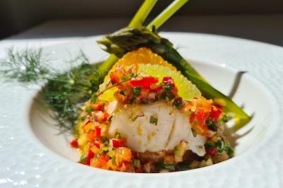 Salle décorée avec des ballons roses, éclairage violet, deux personnes marchant au centre, tables hautes et chaises…