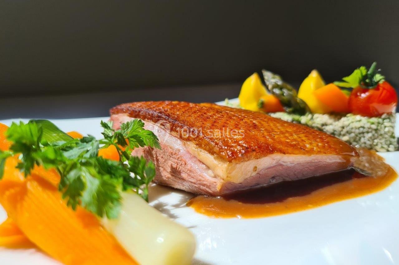 Assiette gastronomique avec magret de canard, carottes, poireau, légumes colorés et sauce, présentée sur une table.