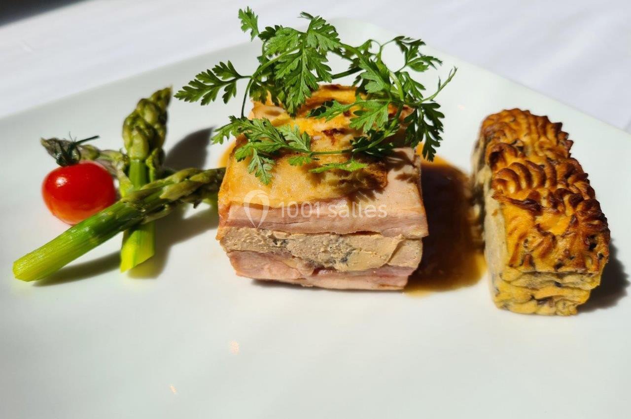 Plat gastronomique composé d'une terrine, d'asperges, d'une tomate cerise et d'un accompagnement gratiné.