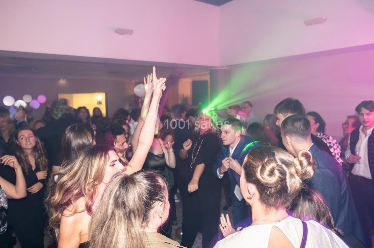 Groupe de personnes dansant et socialisant dans une salle éclairée par des lumières colorées.