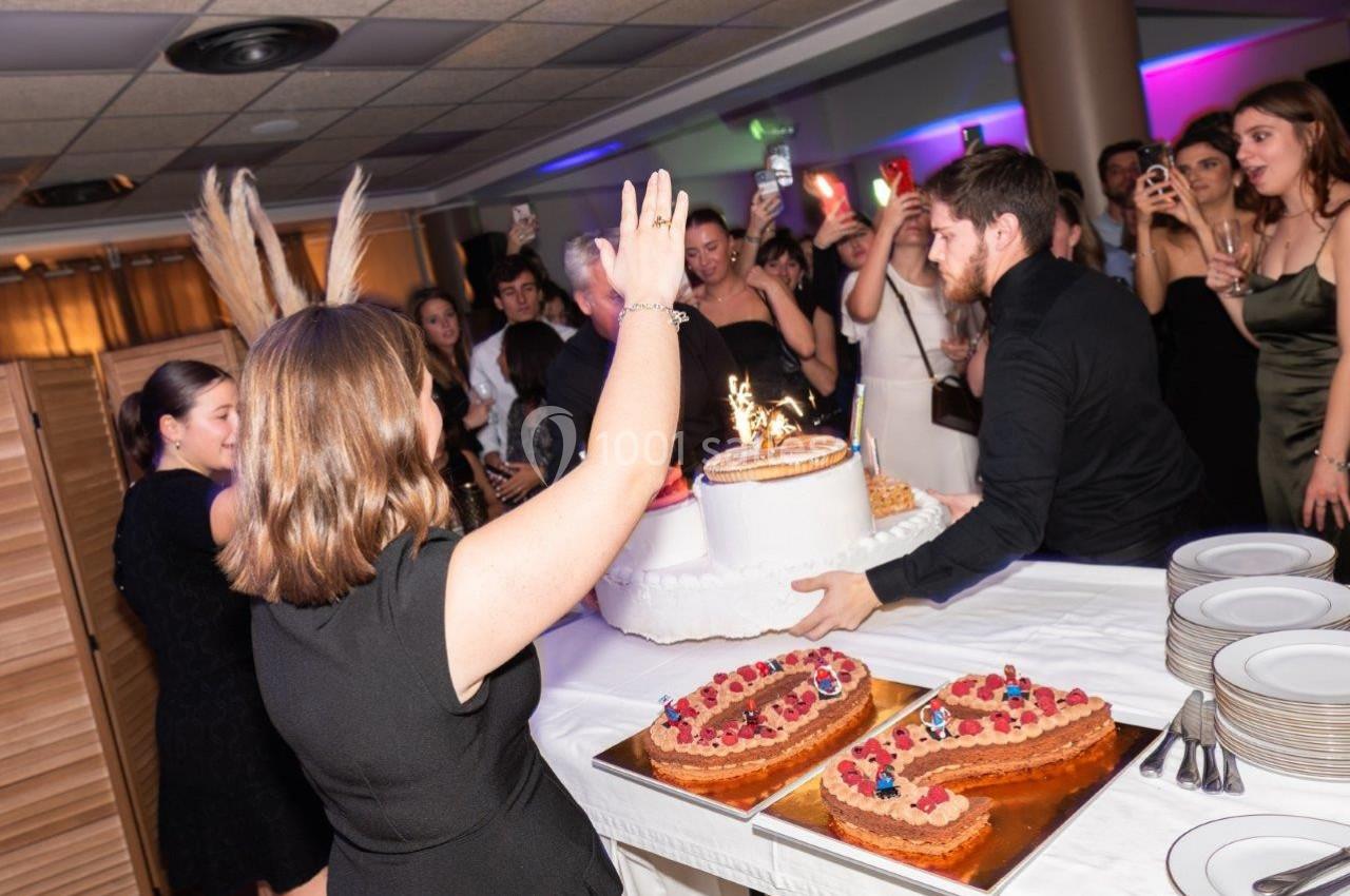 Un homme apporte un gâteau d'anniversaire avec des bougies allumées lors d'une fête entourée d'invités.