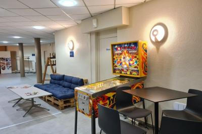 Salle décorée avec des ballons roses, éclairage violet, deux personnes marchant au centre, tables hautes et chaises…