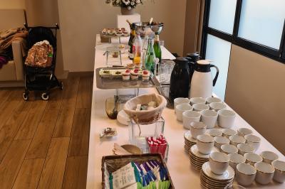 Salle décorée avec des ballons roses, éclairage violet, deux personnes marchant au centre, tables hautes et chaises…