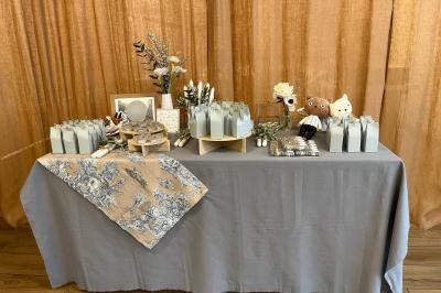 Salle décorée avec des ballons roses, éclairage violet, deux personnes marchant au centre, tables hautes et chaises…