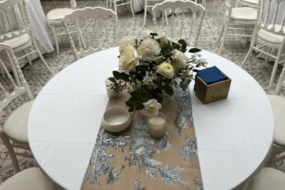 Salle décorée avec des ballons roses, éclairage violet, deux personnes marchant au centre, tables hautes et chaises…