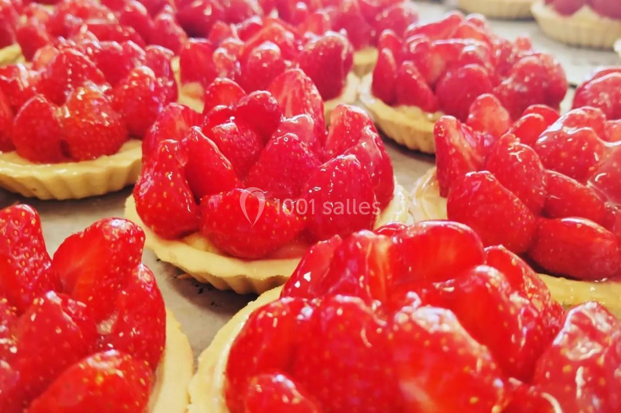 Tartelettes garnies de fraises fraîches et brillantes disposées sur une surface plane.