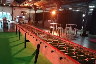 Miniature Traiteur Villetaneuse (Seine-Saint-Denis) - Picgourmet  #17 Baby-foot géant installé dans un espace intérieur avec éclairage tamisé et tables hautes en arrière-plan.