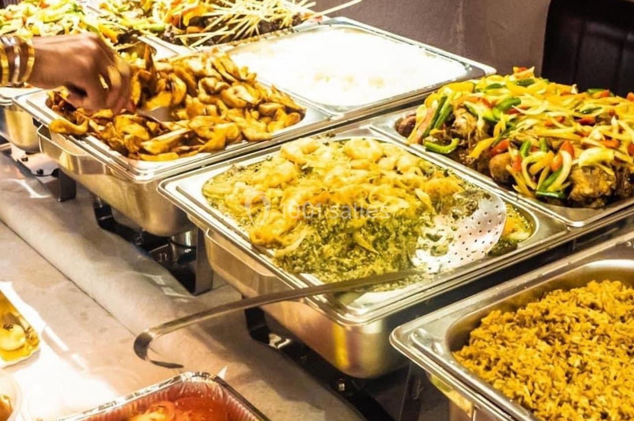 Buffet avec divers plats chauds, incluant du riz, des légumes sautés, des brochettes et des préparations en sauce.