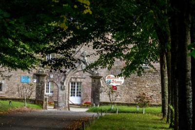 Façade éclairée d'un grand bâtiment en pierre de style ancien, entouré d'une pelouse, de nuit.