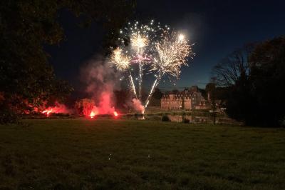 Façade éclairée d'un grand bâtiment en pierre de style ancien, entouré d'une pelouse, de nuit.