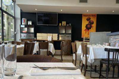 Miniature Location salle Lyon 9 (Rhône) - Le Petit Marché d'Une Faim d'Apprendre #13 Salle lumineuse avec grandes baies vitrées, tables en bois et vue sur une rue calme bordée de bâtiments.