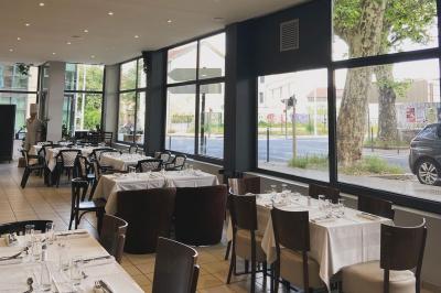 Miniature Location salle Lyon 9 (Rhône) - Le Petit Marché d'Une Faim d'Apprendre #12 Salle lumineuse avec grandes baies vitrées, tables en bois et vue sur une rue calme bordée de bâtiments.