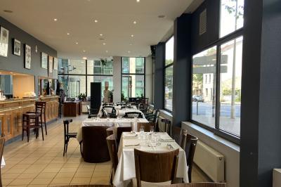 Miniature Location salle Lyon 9 (Rhône) - Le Petit Marché d'Une Faim d'Apprendre #14 Salle lumineuse avec grandes baies vitrées, tables en bois et vue sur une rue calme bordée de bâtiments.