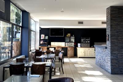 Miniature Location salle Lyon 9 (Rhône) - Le Petit Marché d'Une Faim d'Apprendre #8 Salle lumineuse avec grandes baies vitrées, tables en bois et vue sur une rue calme bordée de bâtiments.