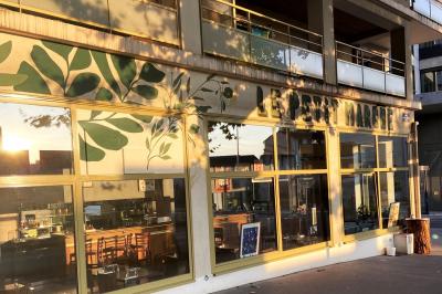 Miniature Location salle Lyon 9 (Rhône) - Le Petit Marché d'Une Faim d'Apprendre #17 Salle lumineuse avec grandes baies vitrées, tables en bois et vue sur une rue calme bordée de bâtiments.