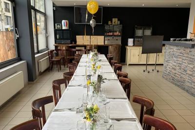 Miniature Location salle Lyon 9 (Rhône) - Le Petit Marché d'Une Faim d'Apprendre #4 Salle lumineuse avec grandes baies vitrées, tables en bois et vue sur une rue calme bordée de bâtiments.