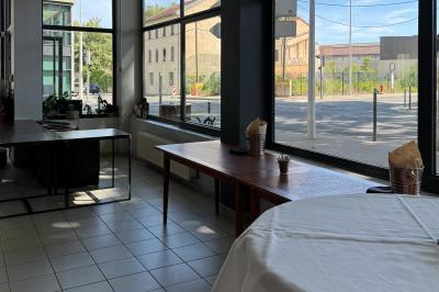 Miniature Location salle Lyon 9 (Rhône) - Le Petit Marché d'Une Faim d'Apprendre #20 Salle lumineuse avec grandes baies vitrées, tables en bois et vue sur une rue calme bordée de bâtiments.