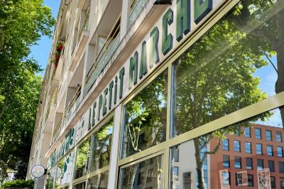 Miniature Location salle Lyon 9 (Rhône) - Le Petit Marché d'Une Faim d'Apprendre #1 Salle lumineuse avec grandes baies vitrées, tables en bois et vue sur une rue calme bordée de bâtiments.