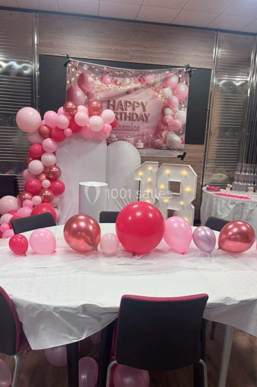 Décoration d'anniversaire avec ballons roses et rouges, panneau ’Happy Birthday’, et chiffre lumineux ’18’.