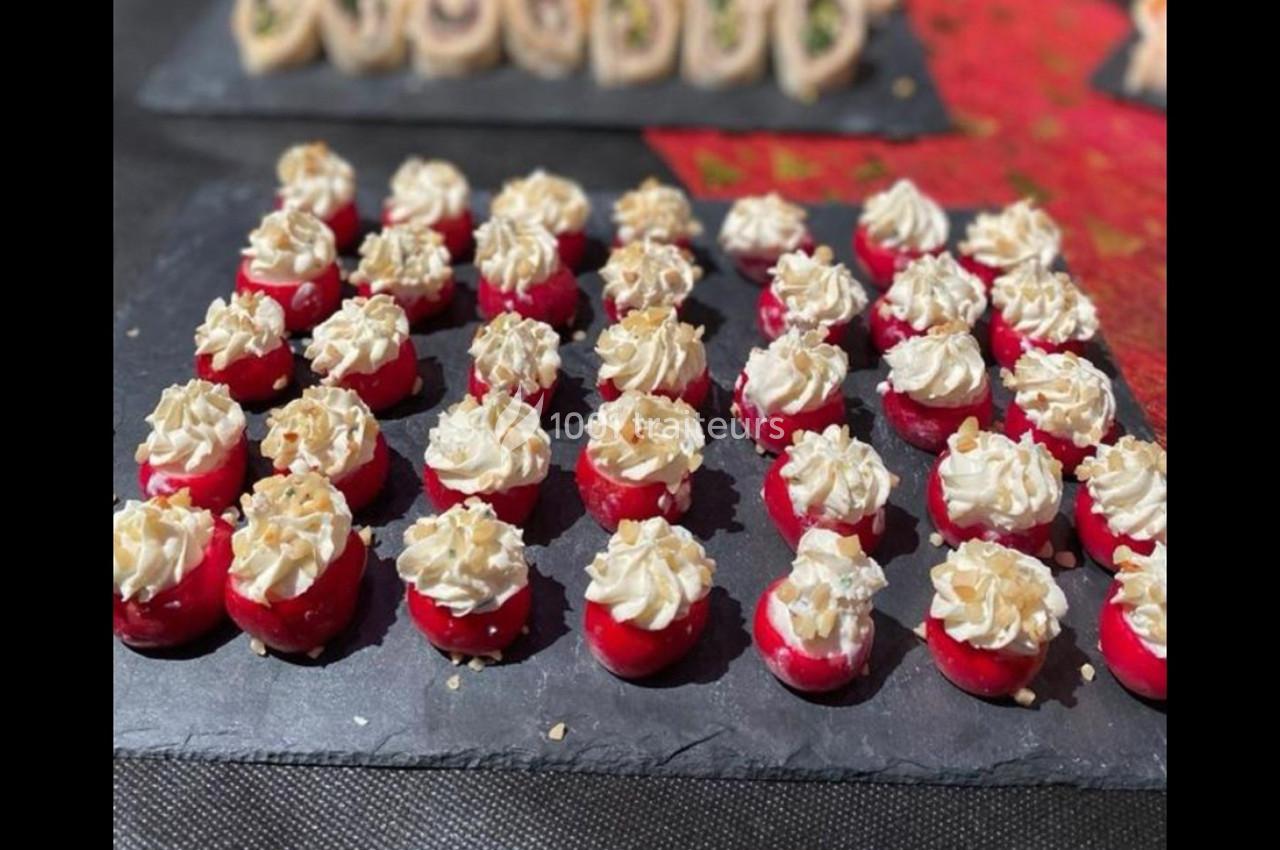 Radis farcis de fromage frais et noix concassées, disposés en rangées sur une ardoise noire.