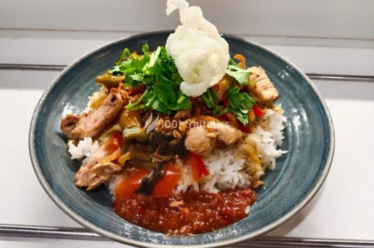 Assiette de riz blanc garnie de légumes, morceaux de poulet, herbes fraîches, sauce rouge et chips croustillantes.