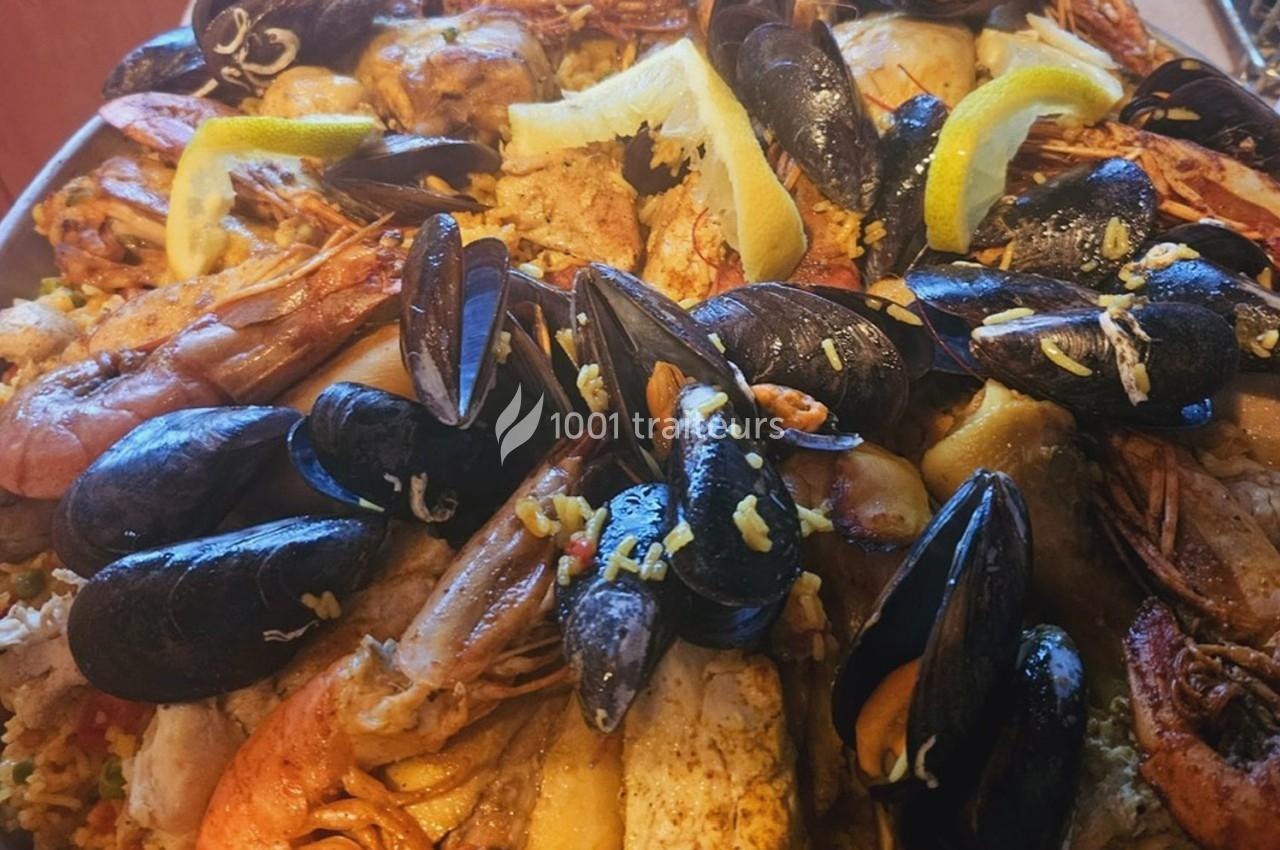 Assiette de fruits de mer variés avec moules, crevettes et quartiers de citron sur un lit de riz.