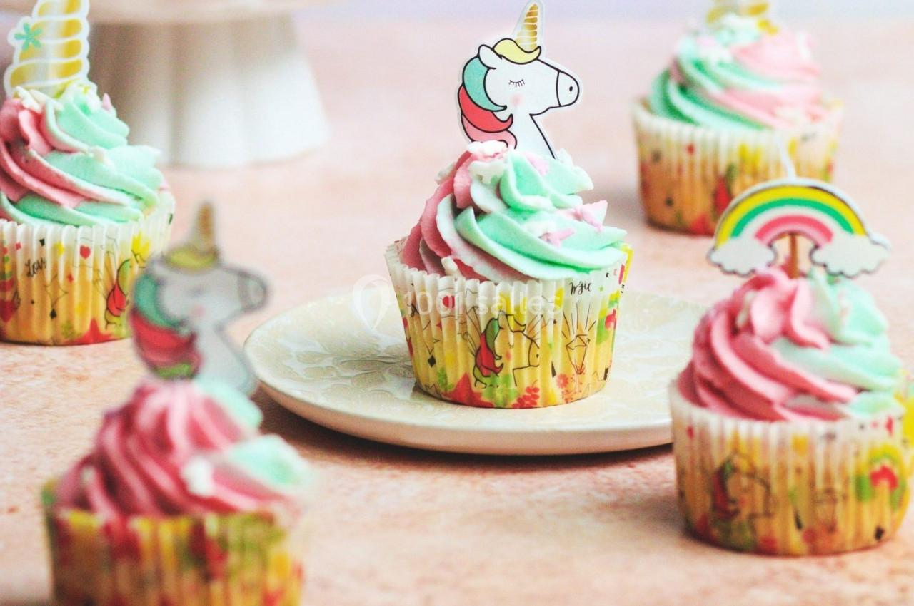 Cupcakes décorés de glaçage rose et vert pastel, ornés de motifs de licornes et d'arc-en-ciel.