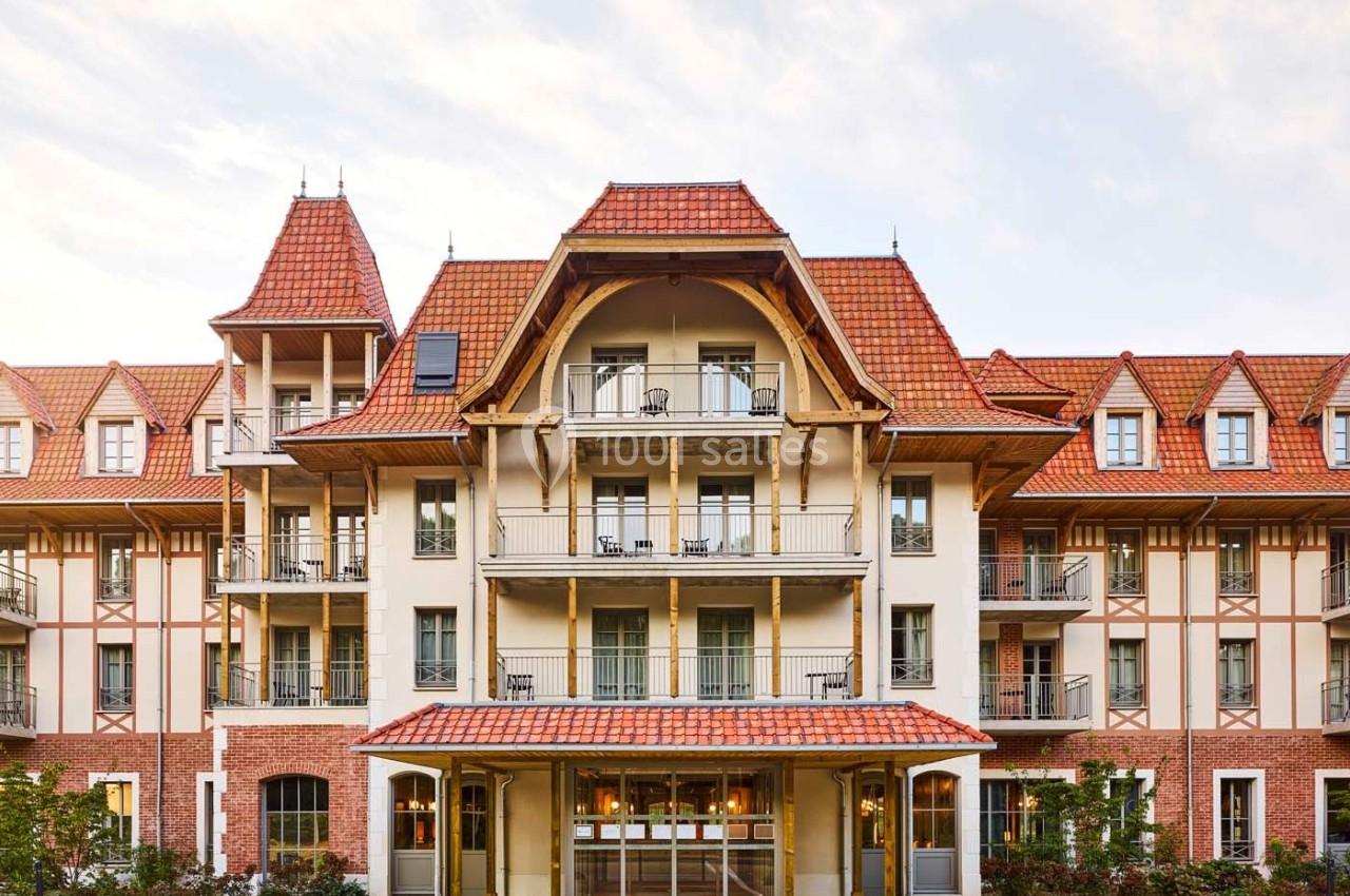 Façade d'un bâtiment à l'architecture traditionnelle avec toit en tuiles rouges et balcons en fer forgé.