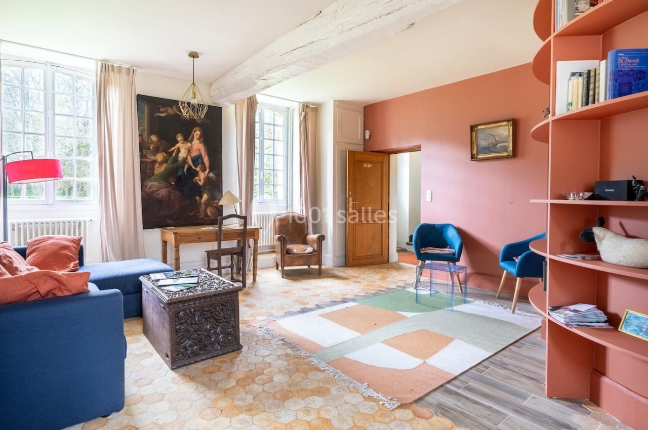 Salon lumineux avec murs terracotta, mobilier éclectique, grande fenêtre, tableau classique et étagère courbée.