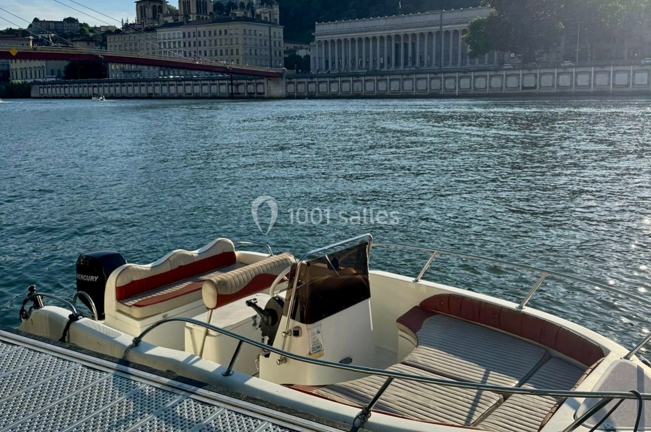 Bateau amarré sur une rivière avec des bâtiments historiques et une colline en arrière-plan.