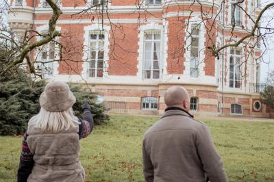 Costume de mariage bleu foncé avec chemise blanche et nœud papillon floral, suspendu sur un cintre gravé.