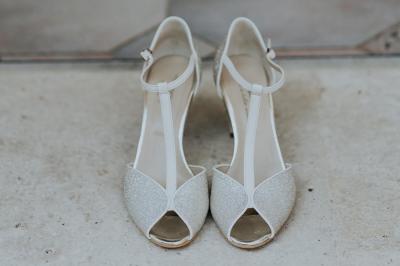 Costume de mariage bleu foncé avec chemise blanche et nœud papillon floral, suspendu sur un cintre gravé.