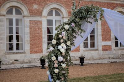 Costume de mariage bleu foncé avec chemise blanche et nœud papillon floral, suspendu sur un cintre gravé.